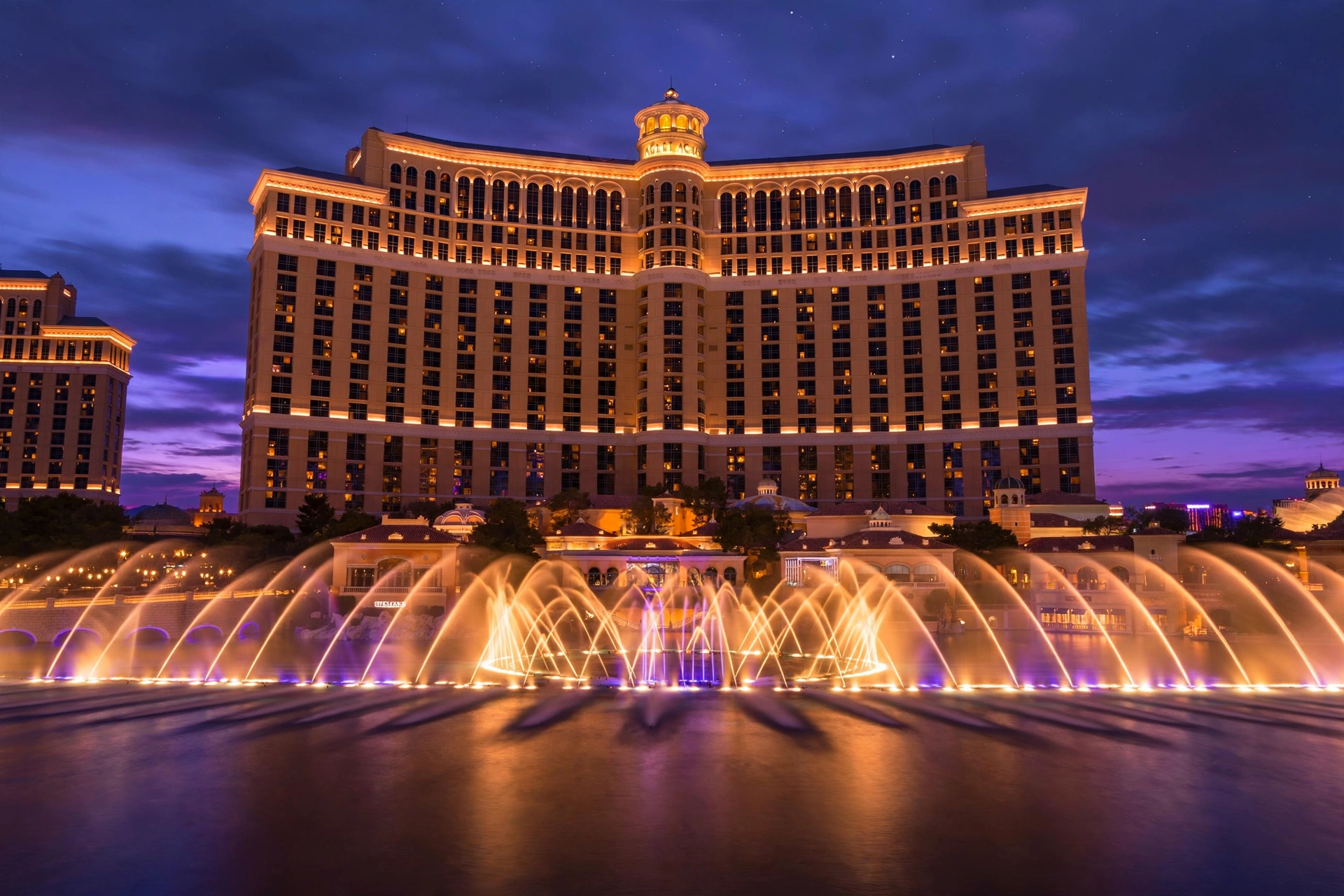 Bellagio resort exterior and illuminated fountain lake at dusk
